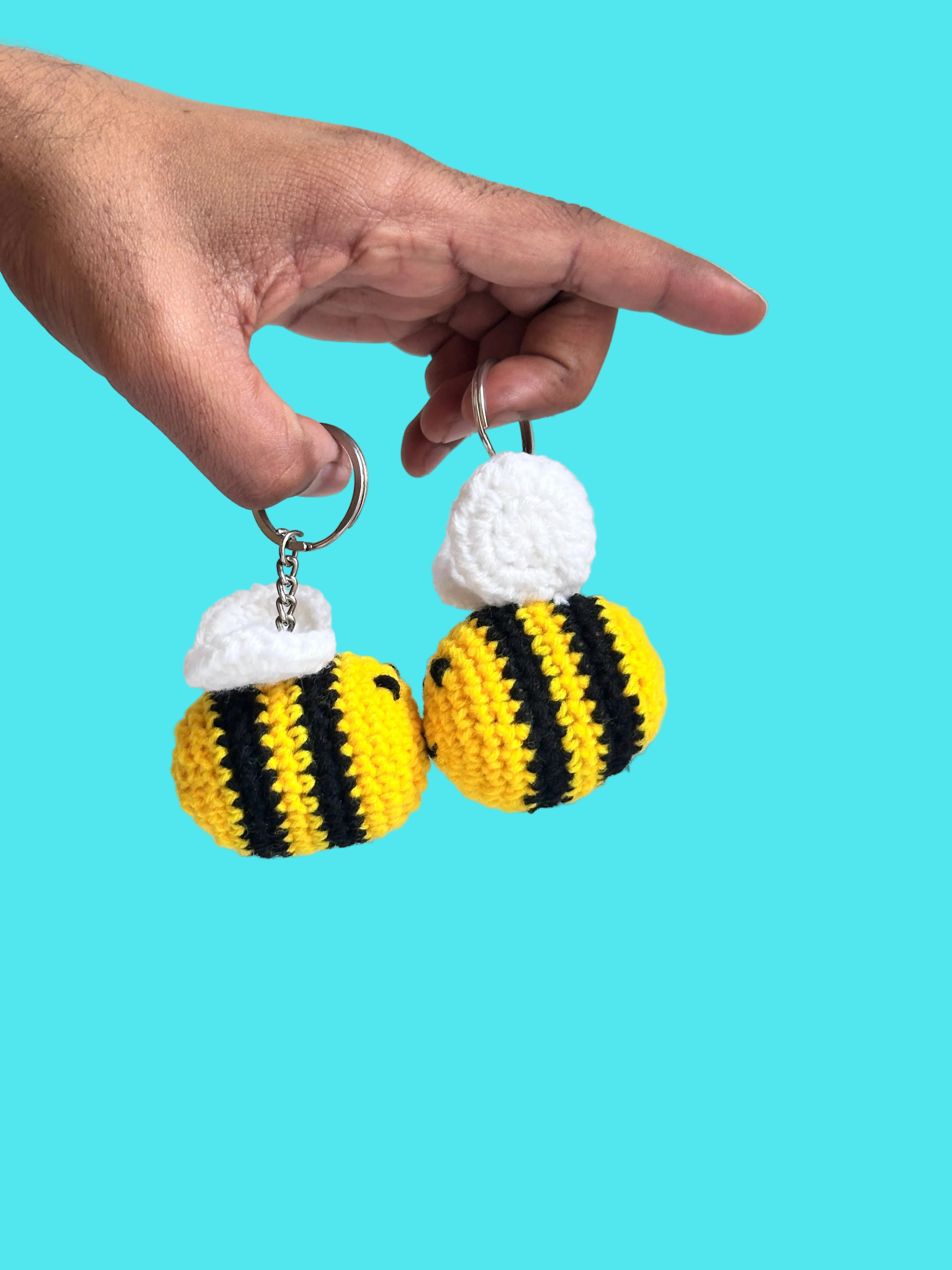 Hand holding a crochet bee keychain against a plain background
